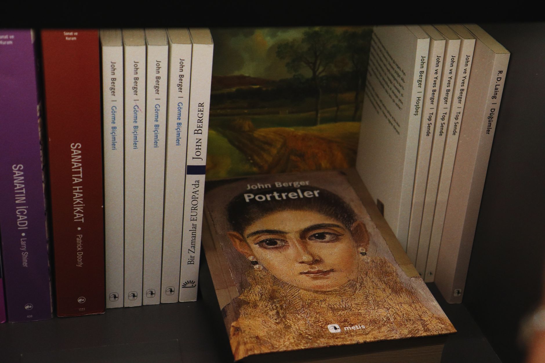 Bookshelves with a selection of John Berger's books featuring an artistic portrait cover.