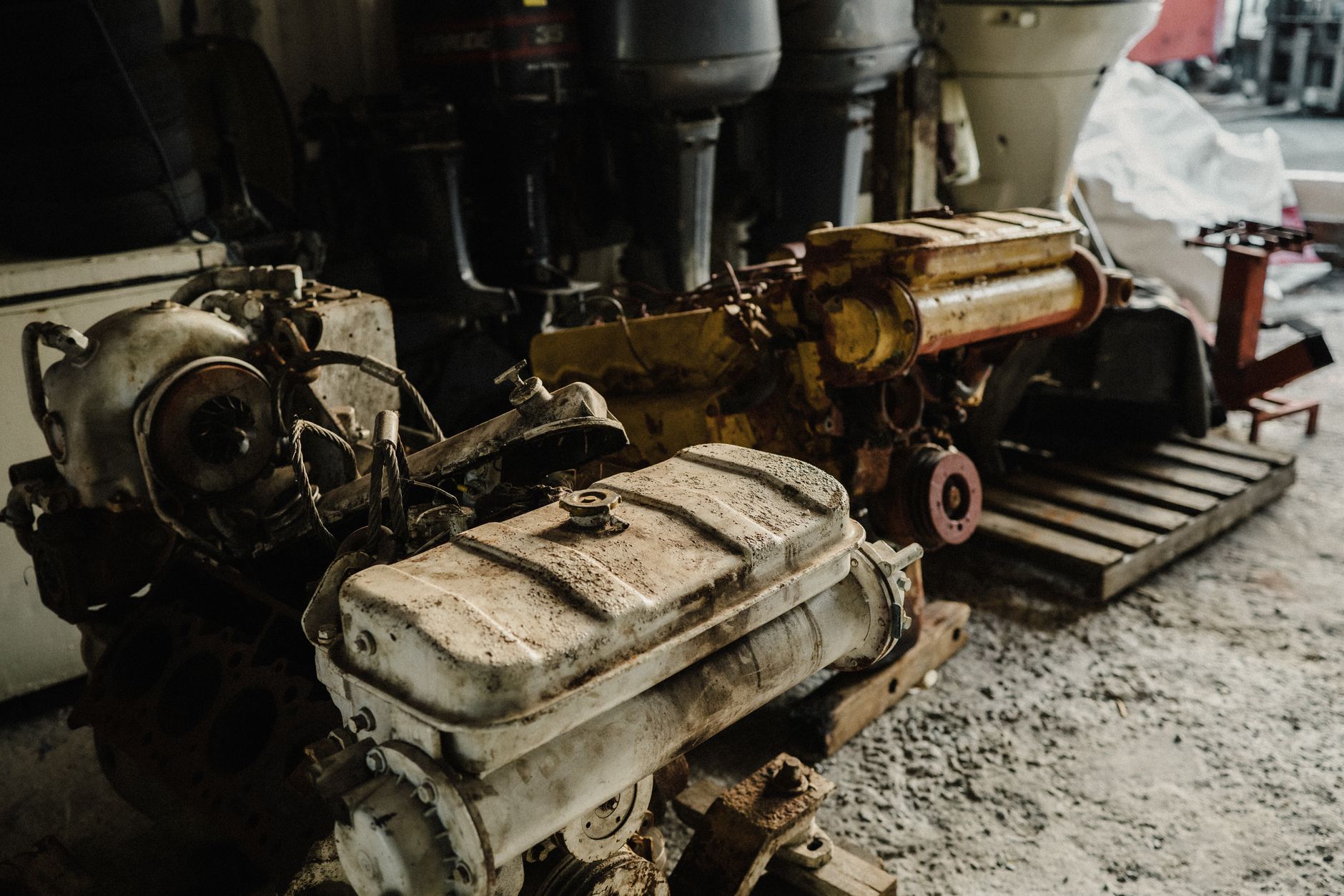 A collection of used car engines stored in an industrial workshop setting.