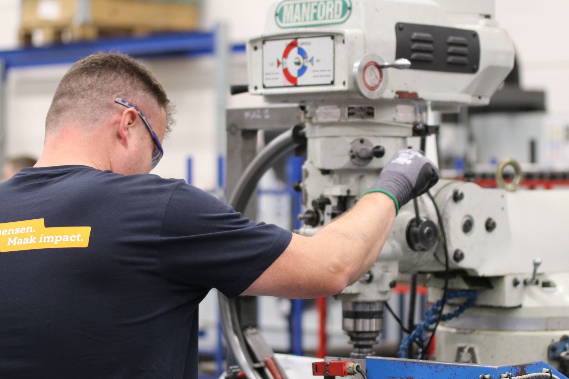 A worker operates a Manford milling machine in an industrial setting, showcasing precision and efficiency.