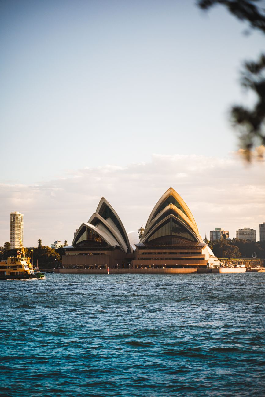 Scenic view of Sydney Opera House and bustling harbor in cloudy weather, New South Wales, Australia.