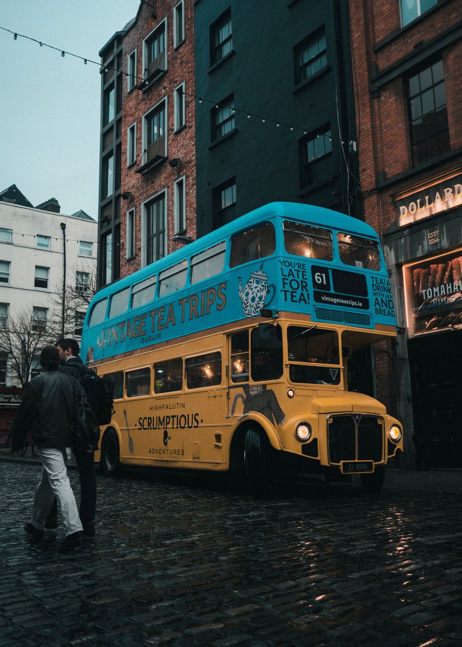 A bustling urban street with red brick buildings and a green bus passing by.