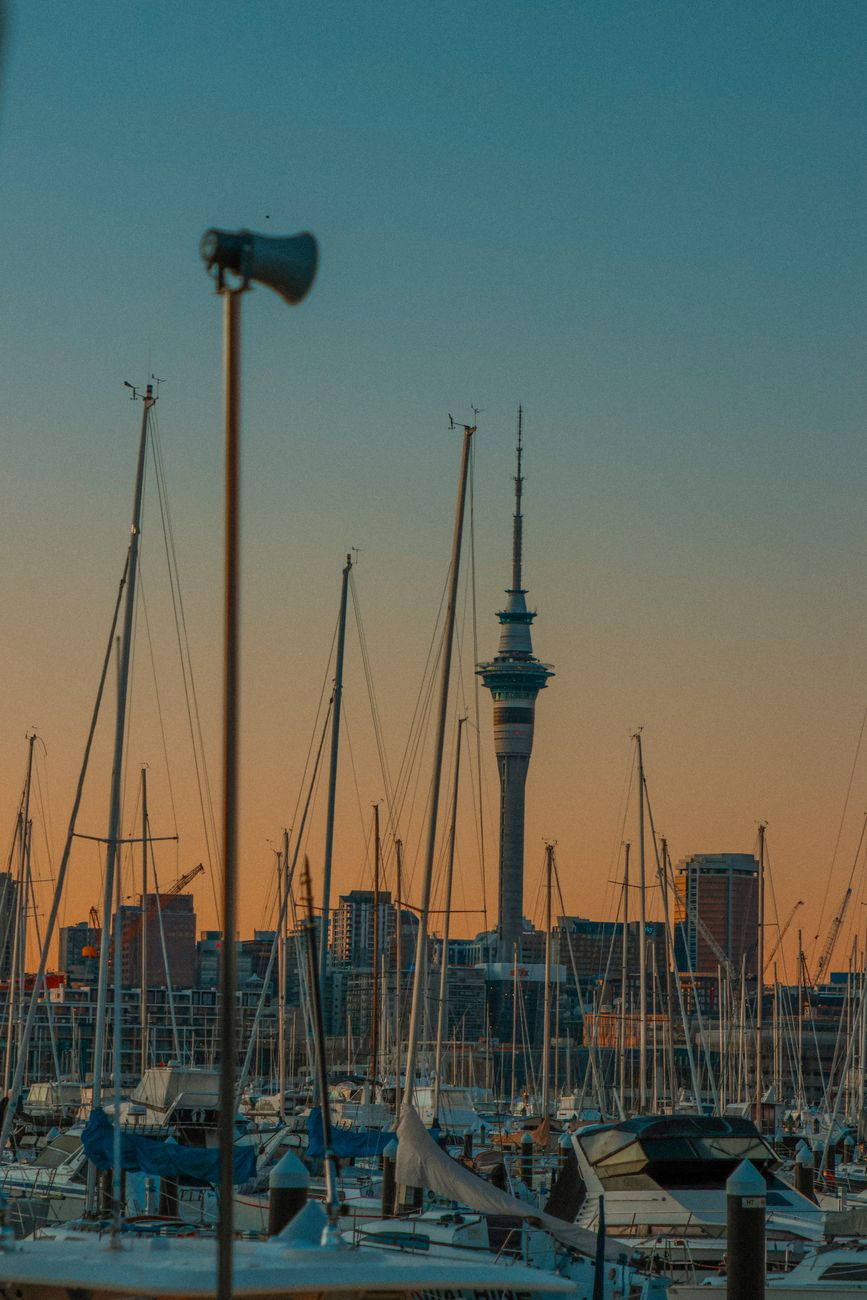 Aerial view of Auckland skyline, harbor, and bridge under clear sky.
