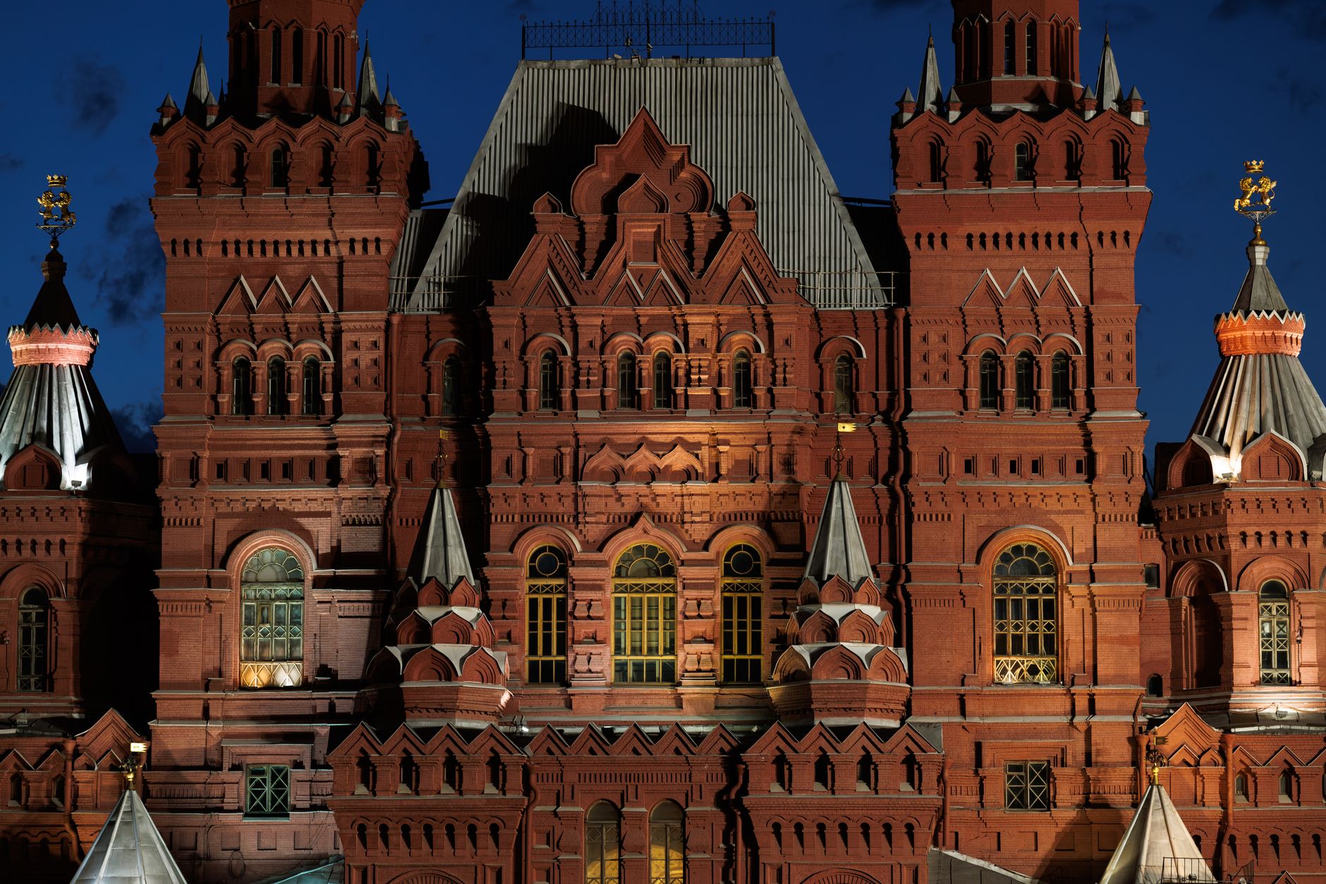 Illuminated facade of the State Historical Museum in Moscow at night.