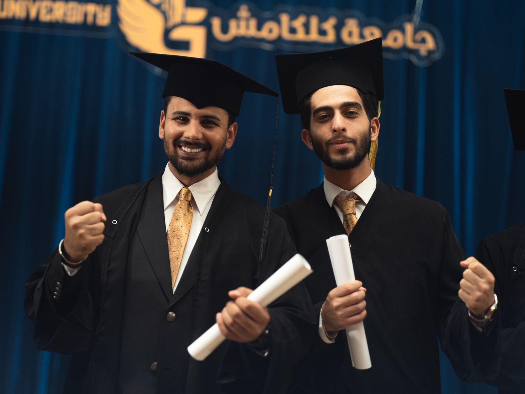 Two male graduates in caps and gowns celebrate their achievement in Baghdad, Iraq.