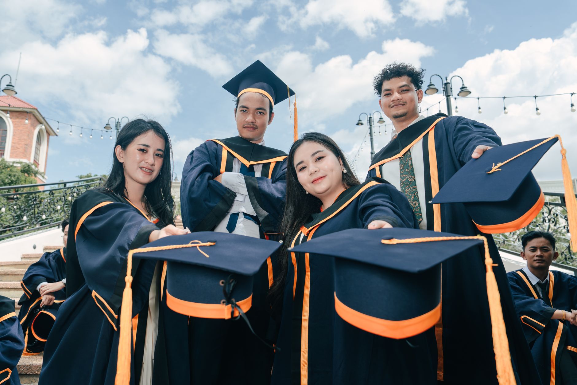 A group of young adults celebrating their graduation with caps and gowns outdoors.