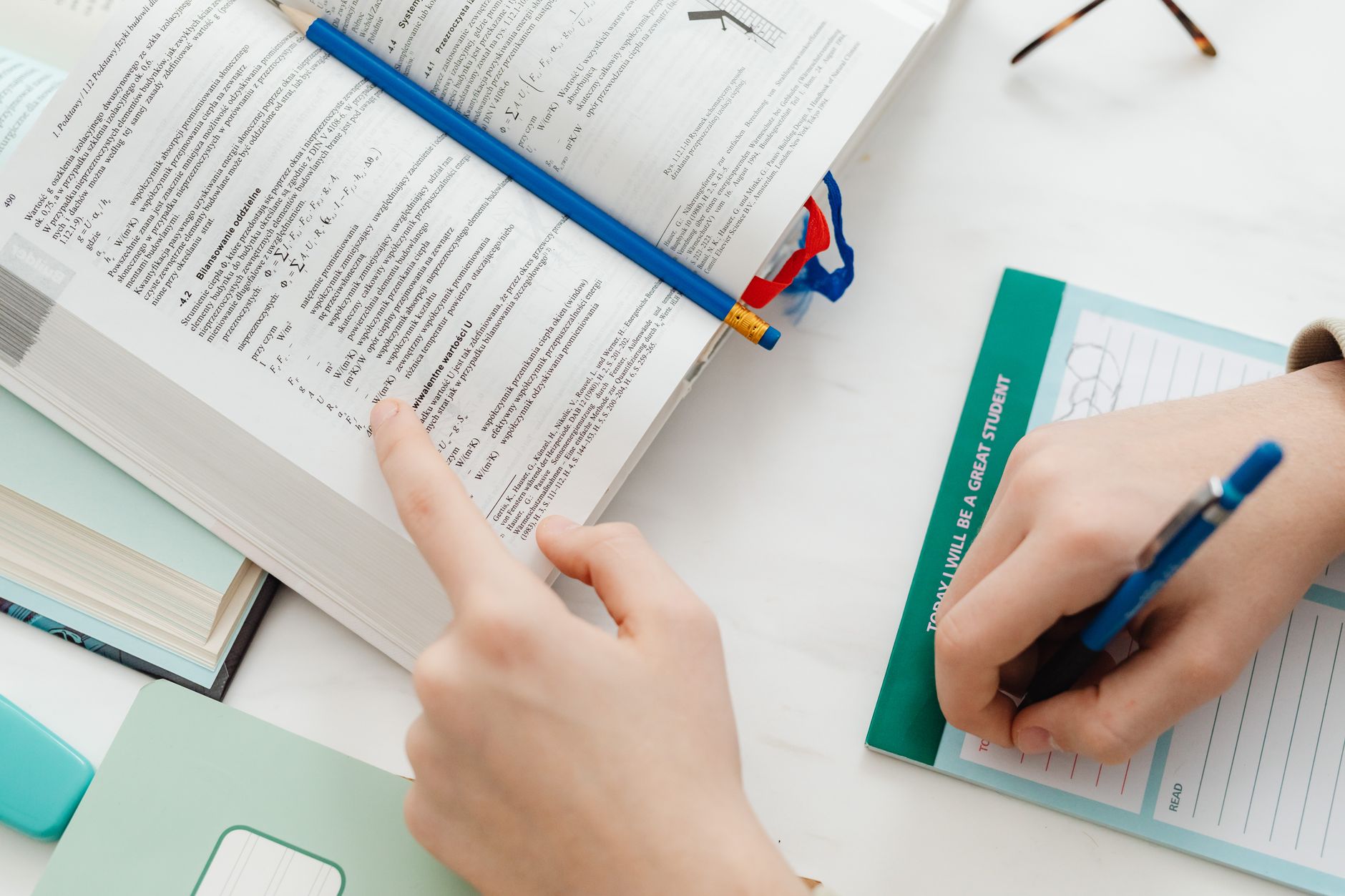 Close-up of a student studying mathematics from an open book with notes on the table.