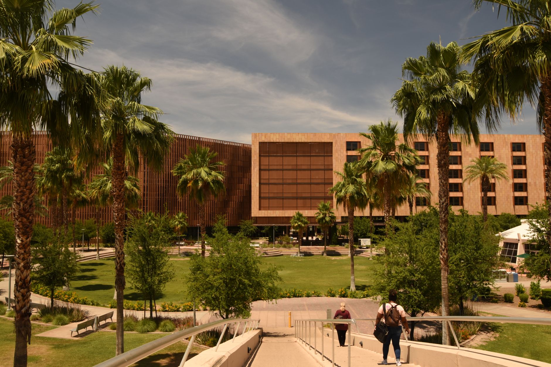A modern building with palm trees on a sunny university campus.