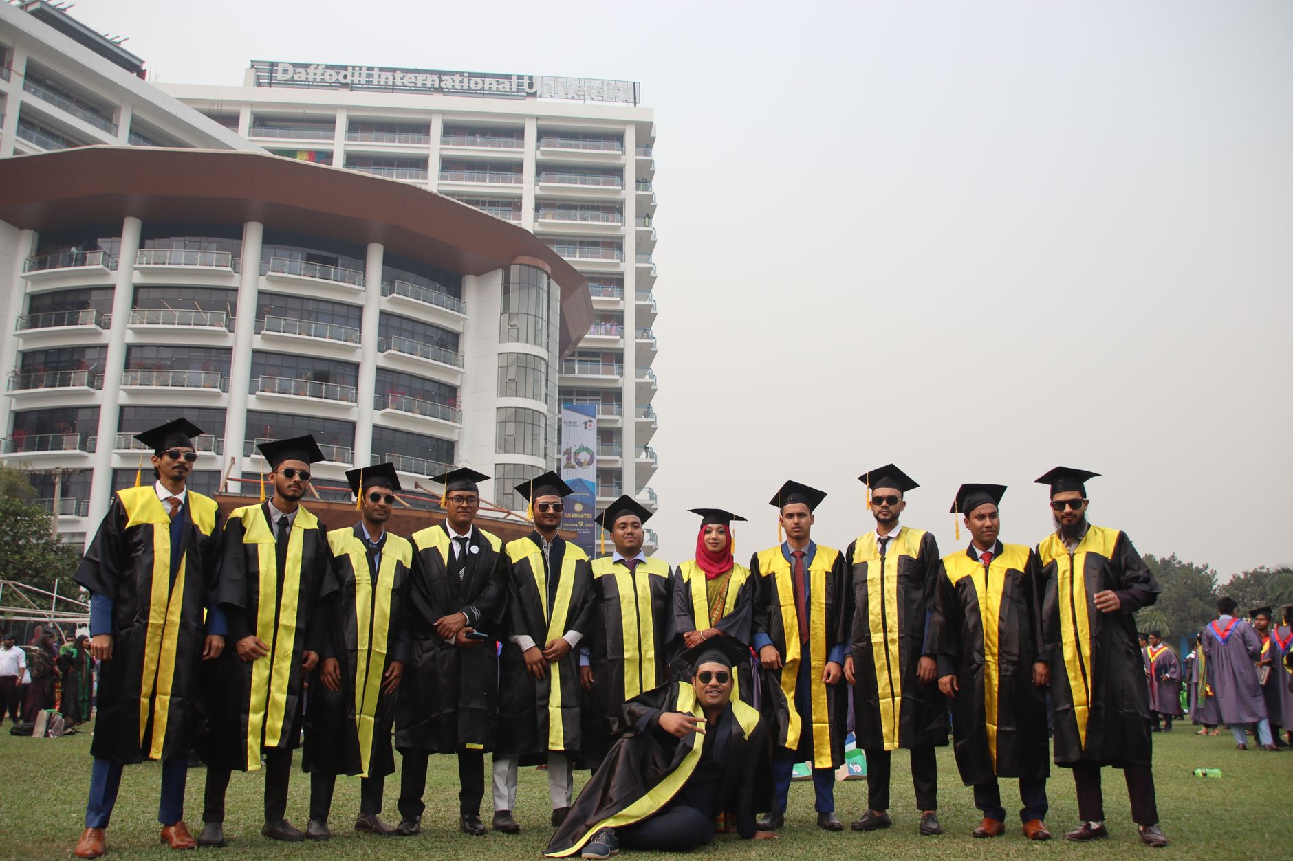 Graduating students celebrating with friends in front of university building.