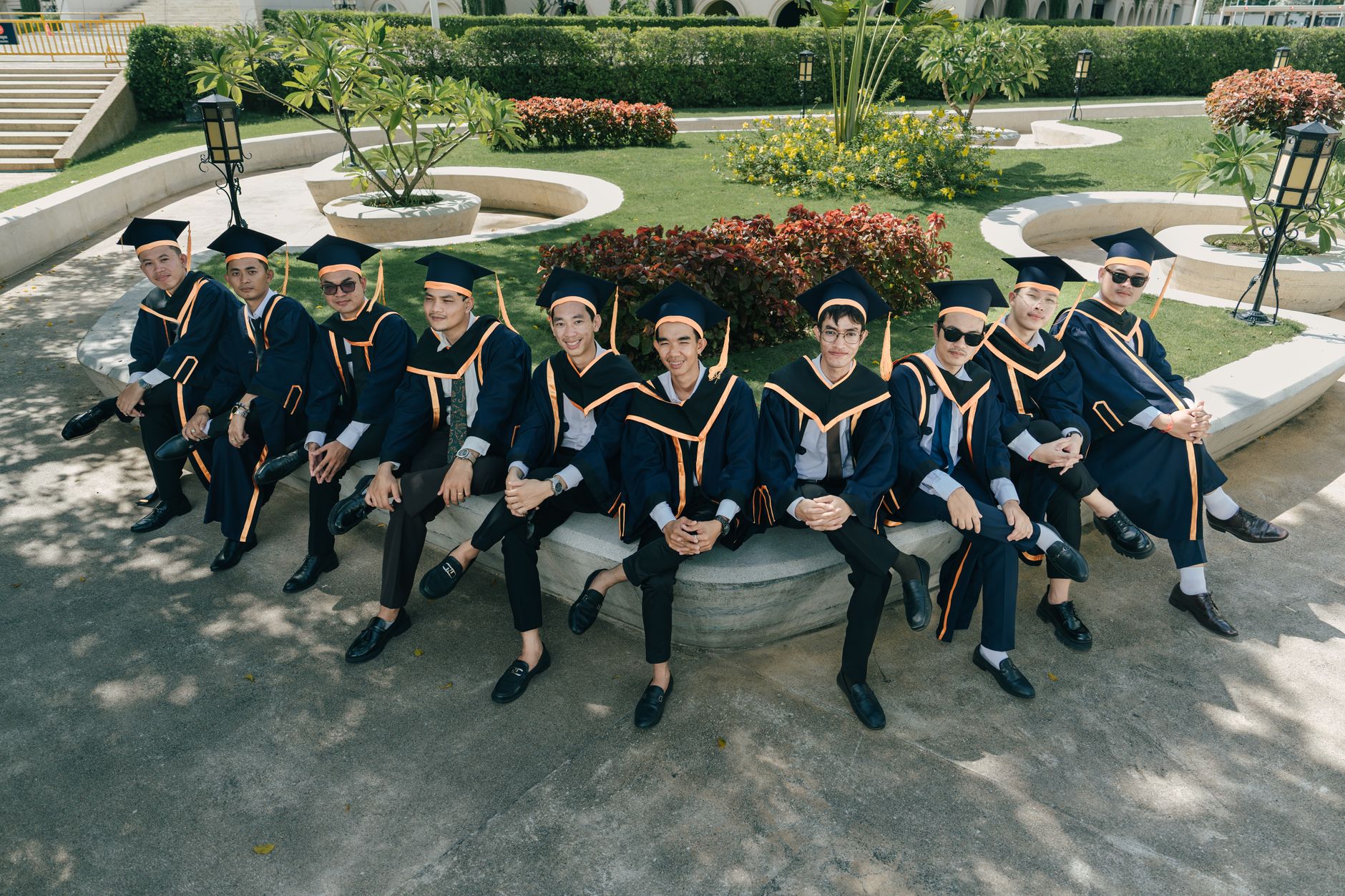 A joyful group of graduates in academic regalia captured outdoors, seated and smiling.